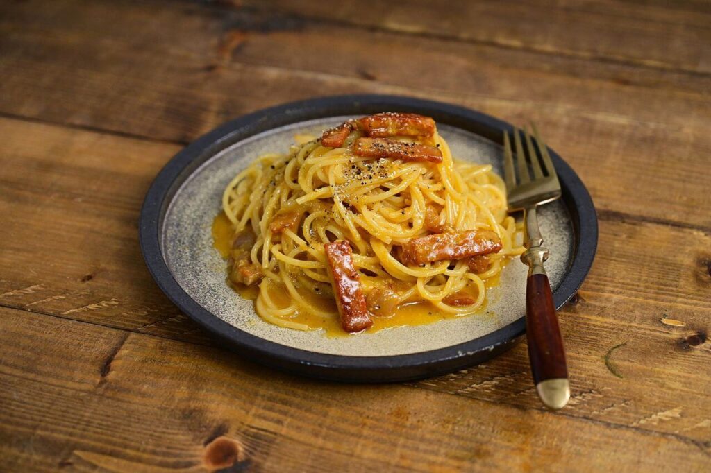 Ingredients for creamy bacon pasta — penne, bacon, heavy cream, and Parmesan