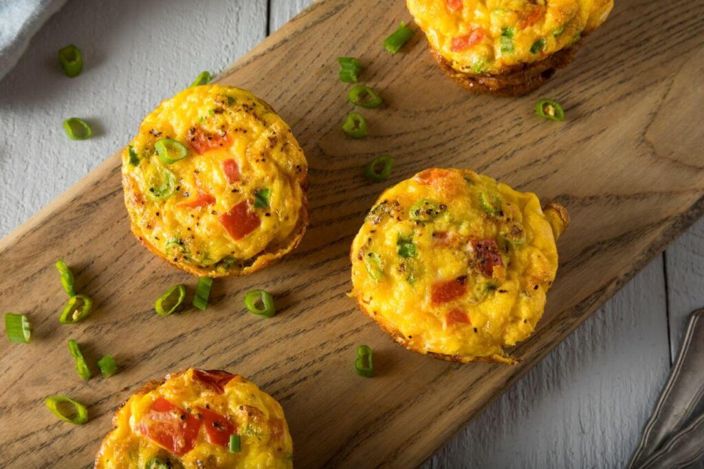 Breakfast egg muffins with melted cheddar on top in a muffin tin